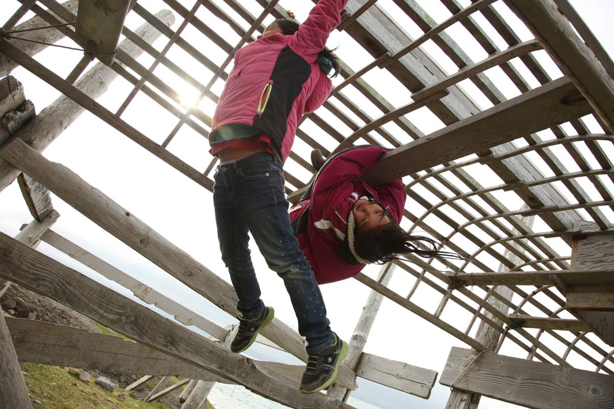Two children playing on a wooden climbing structure