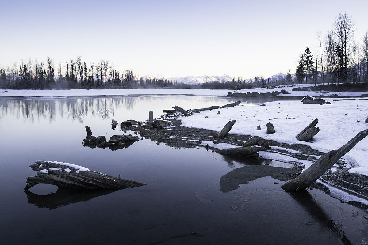 A lake in the wintertime, banks covered in ice and snow